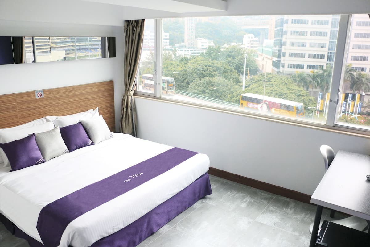 Ein Hotelzimmer mit Bett, Schreibtisch und Fenster mit Blick auf die Stadt.