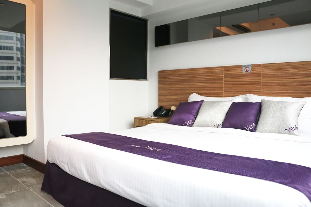 Ein Hotelzimmer mit einem großen Bett, einem hölzernen Kopfteil und einem Nachttisch mit Telefon.