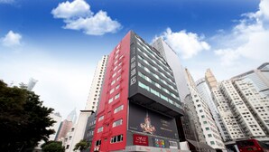 A multi-story hotel with a prominent red and black facade, large windows, and a billboard advertising a hotel chain. - Vela Boutique Hotel (Hong Kong)