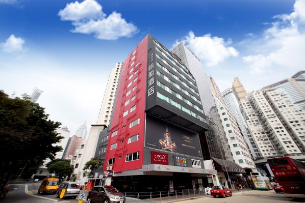 A multi-story hotel with a prominent red and black facade, large windows, and a billboard advertising a hotel chain. - Vela Boutique Hotel (Hong Kong)