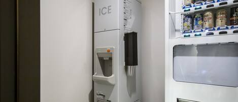 A vending machine with a beverage dispenser and a shelf stocked with cans.