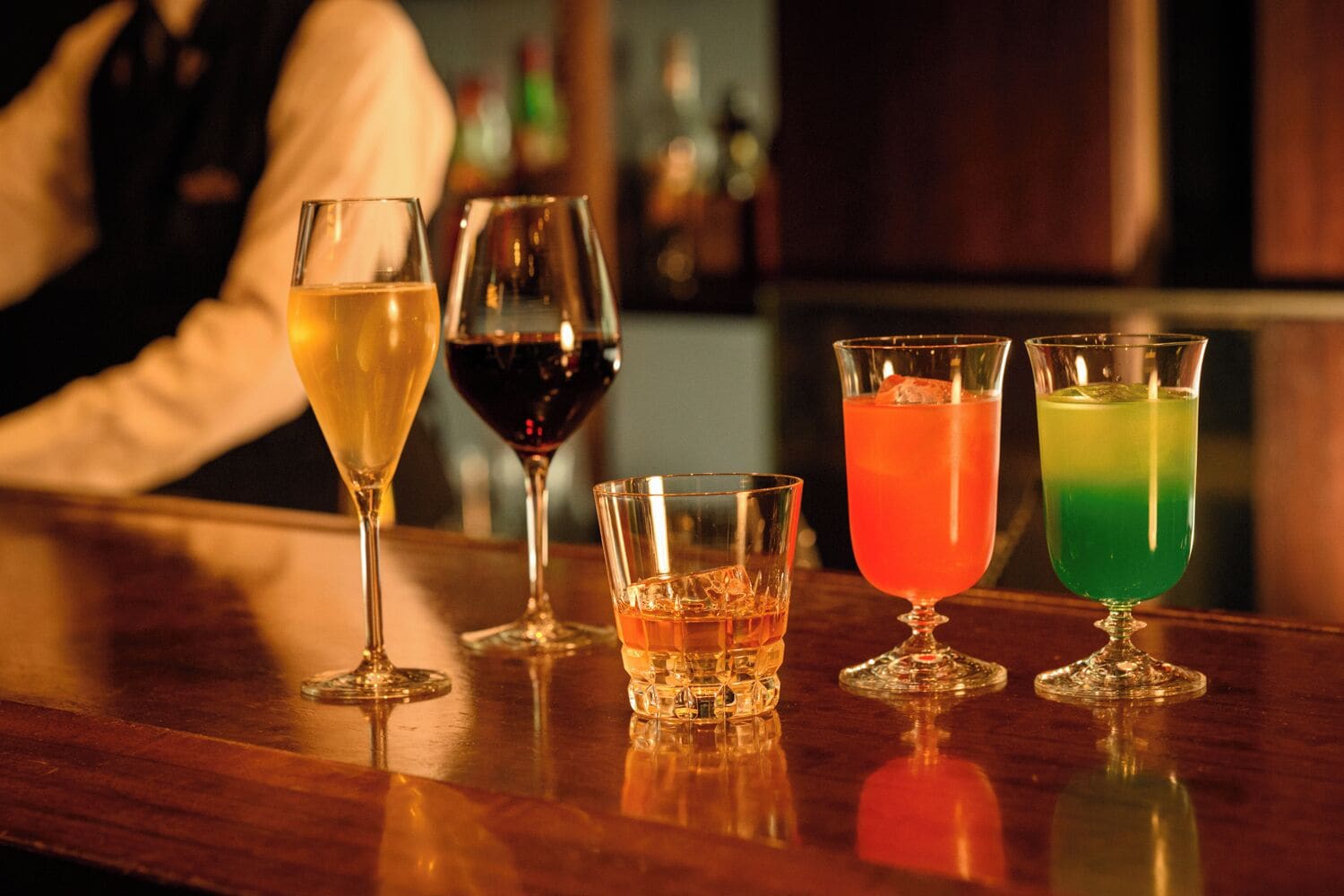 A bar with various glasses of beverages.