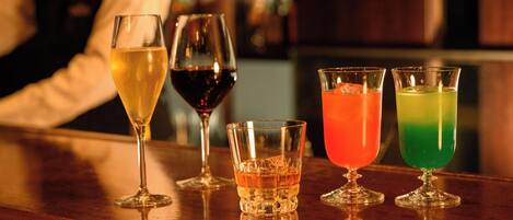 A bar with various glasses of beverages.