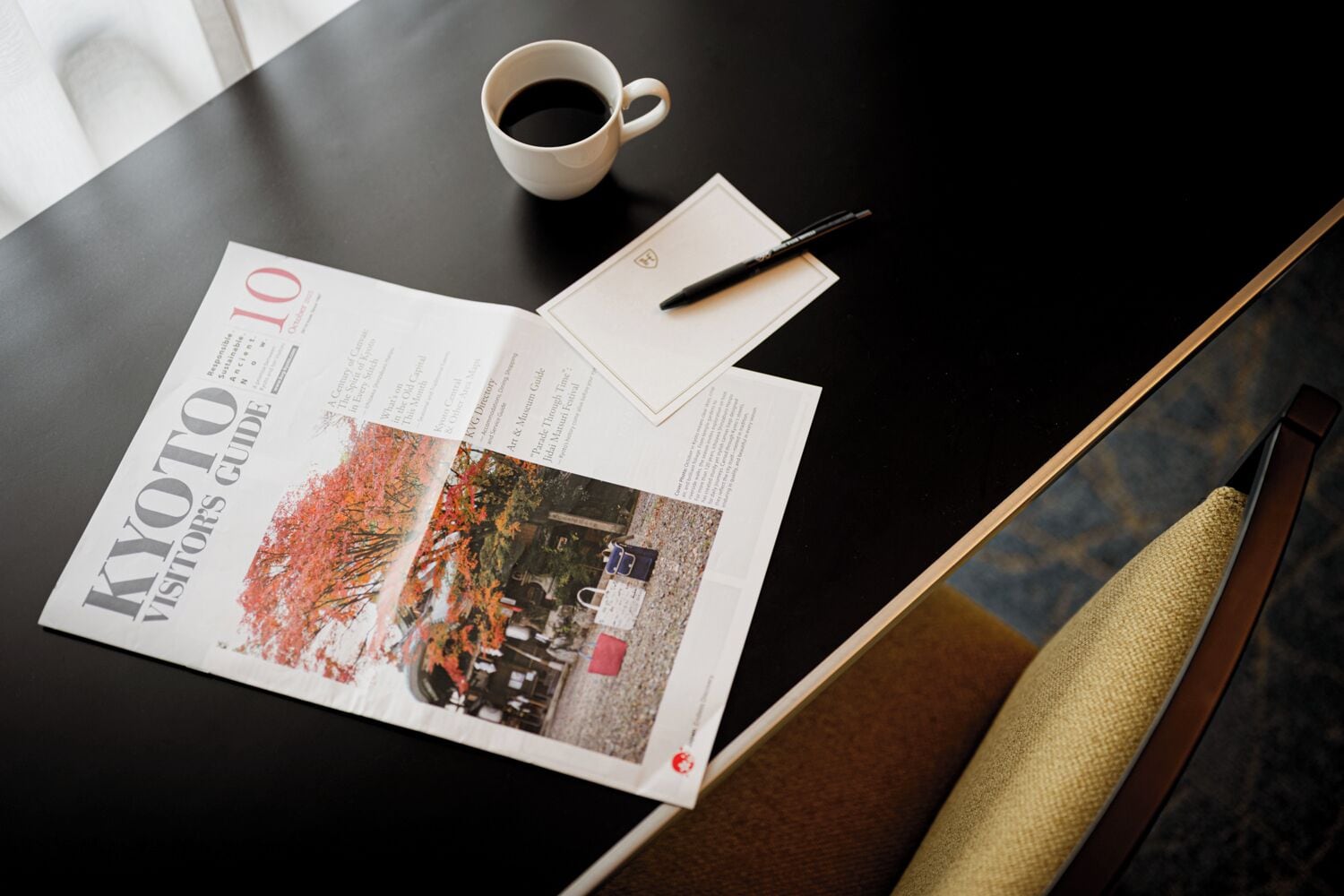 En tidning ligger uppslagen på ett bord, bredvid står en kaffekopp och en penna.