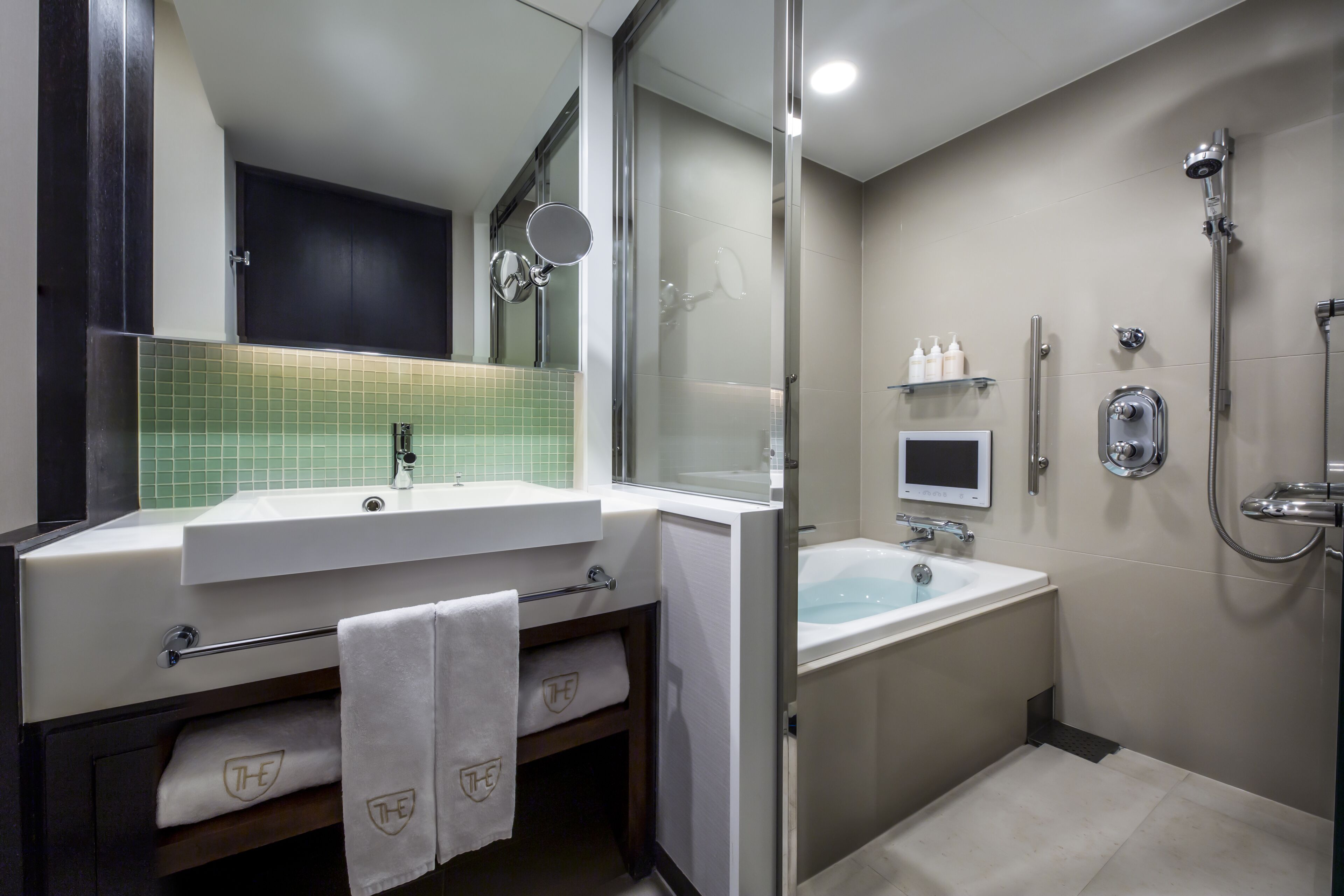 Une salle de bain moderne dotée d’un meuble-lavabo à deux vasques, d’une douche à parois de verre et de toilettes intégrées.