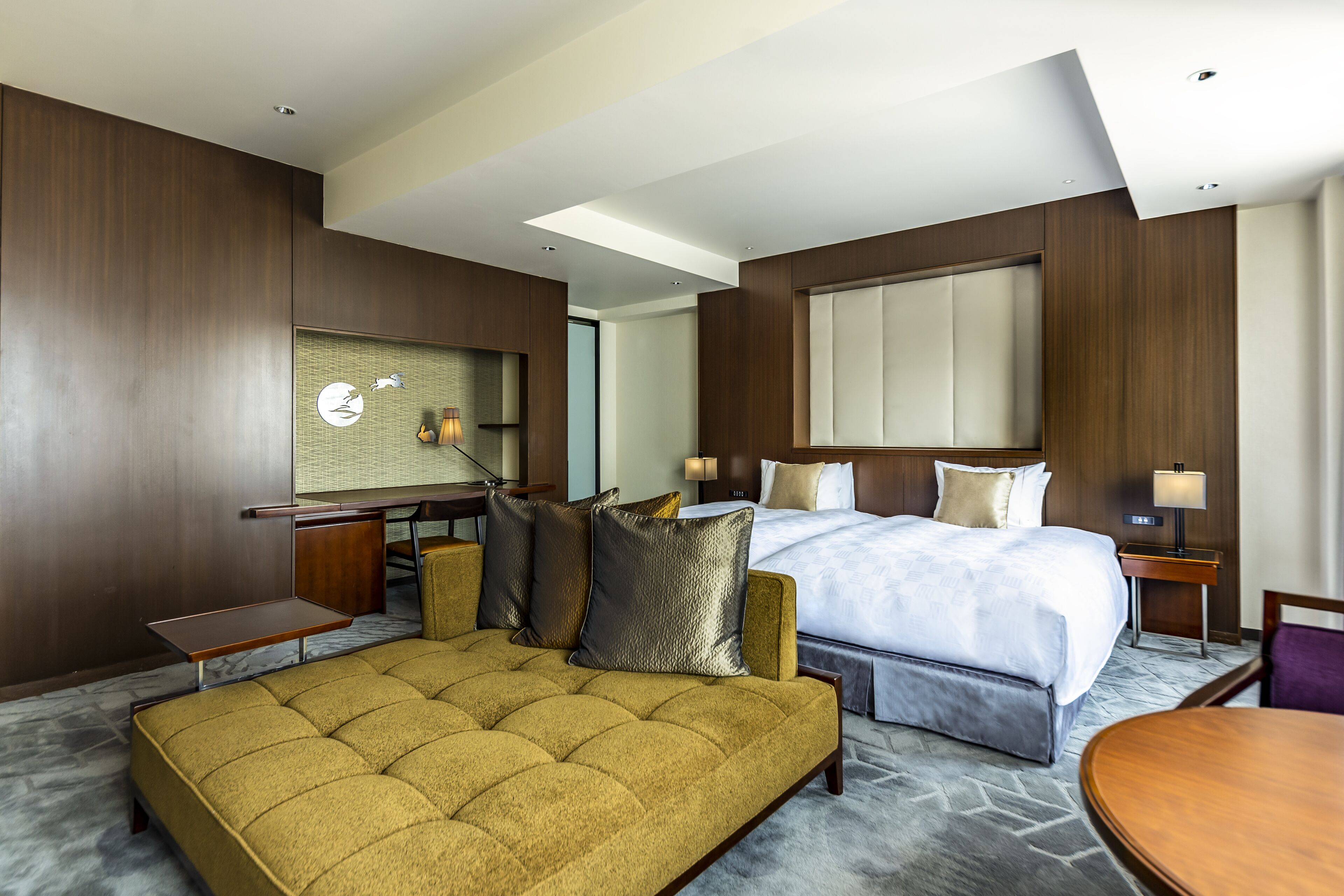 A hotel room with a large bed, a sofa, a desk, and a mirror.