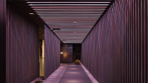 A corridor with vertical wooden panels and a tiled floor, leading to a room with a visible sign. - The Royal Park Hotel Kyoto Sanjo (Kyoto)