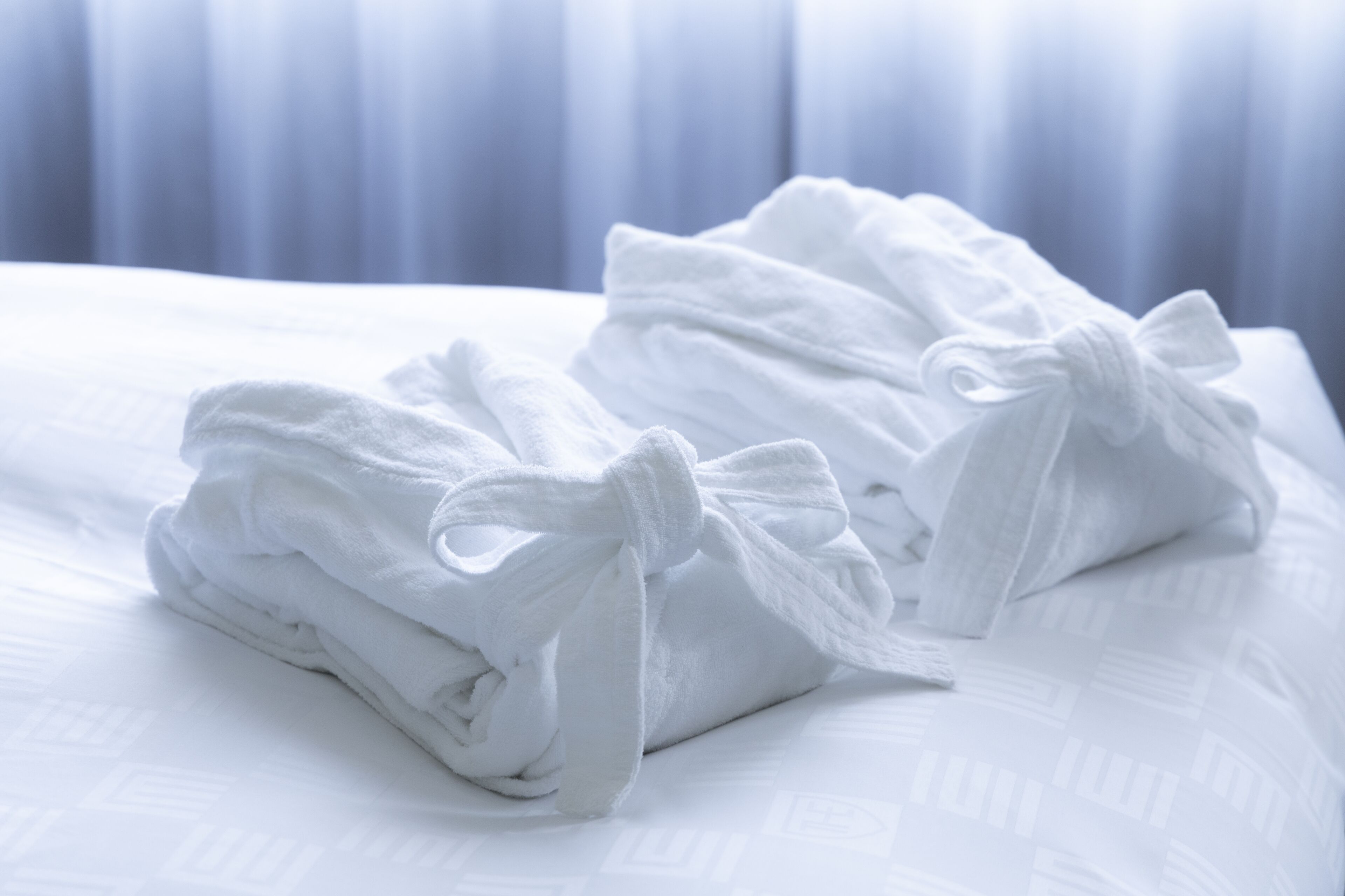 Neatly folded white towels with bows on a bed.