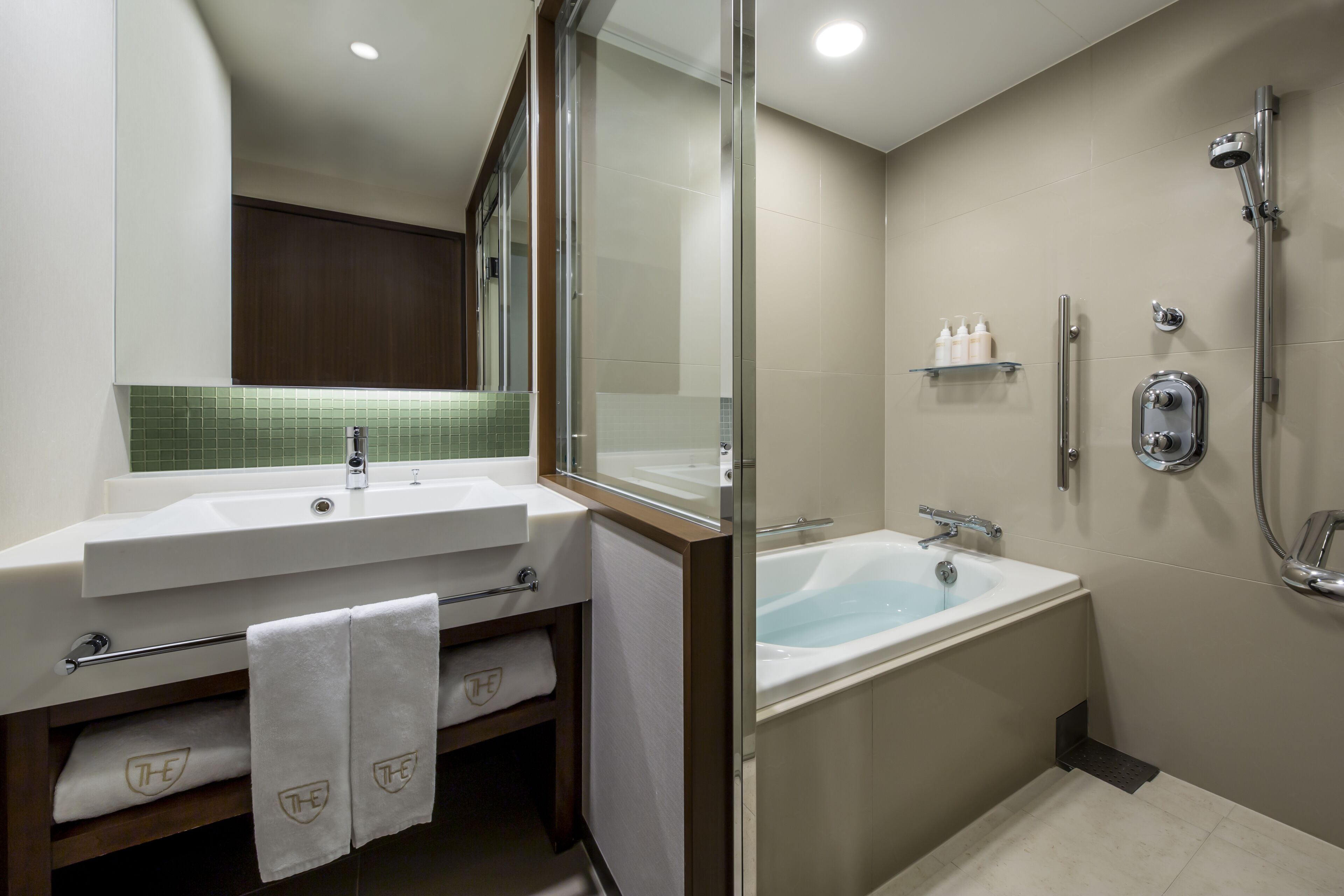 Un baño moderno con una bañera grande, cabina de ducha con mampara de vidrio y tocador con espejo.