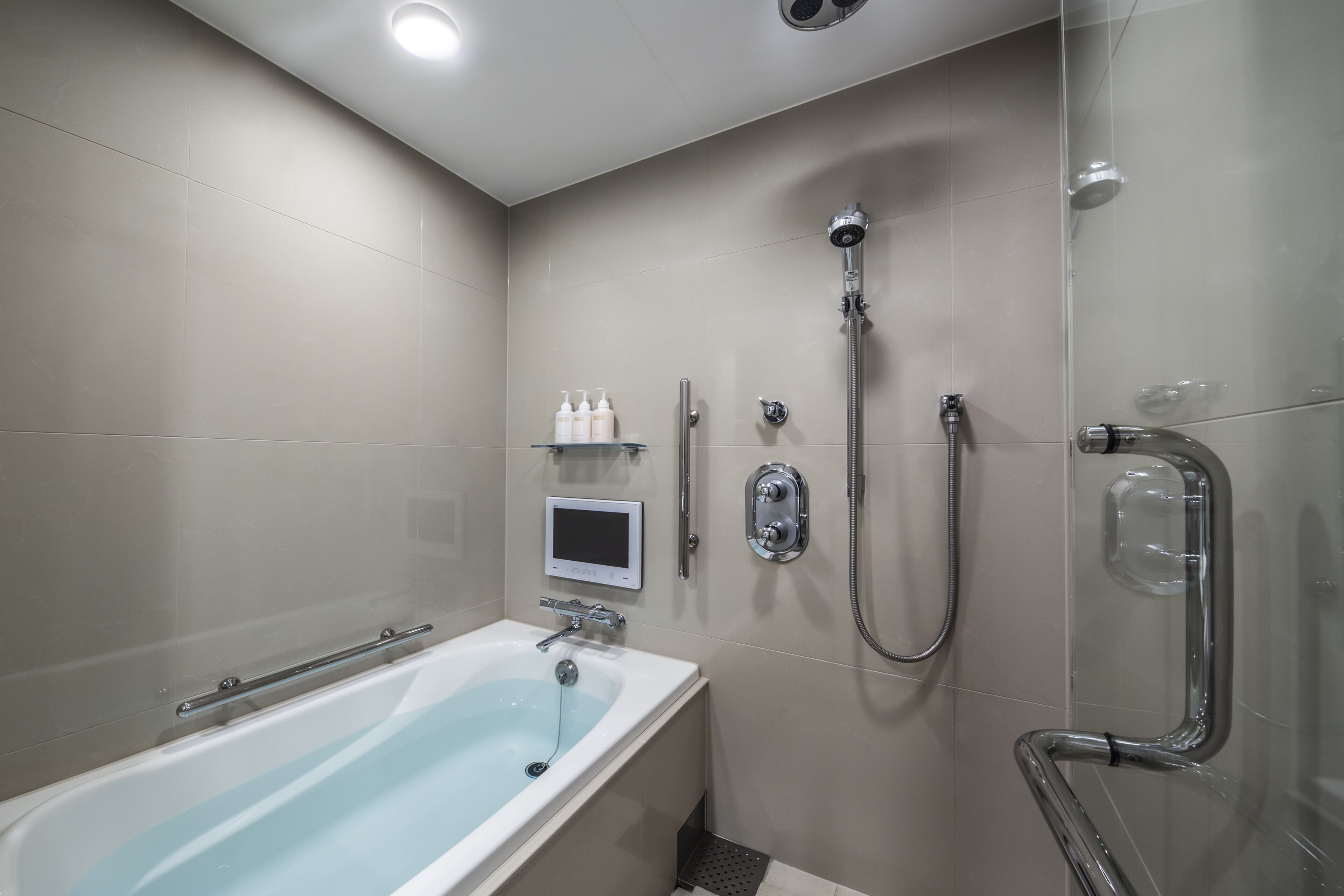 A modern bathroom with a bathtub, shower, and a digital control panel.