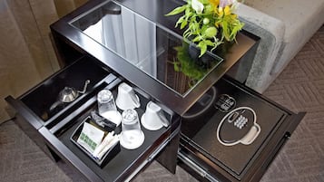 A compact, modern minibar with a glass top, a coffee station, and a small decorative plant.