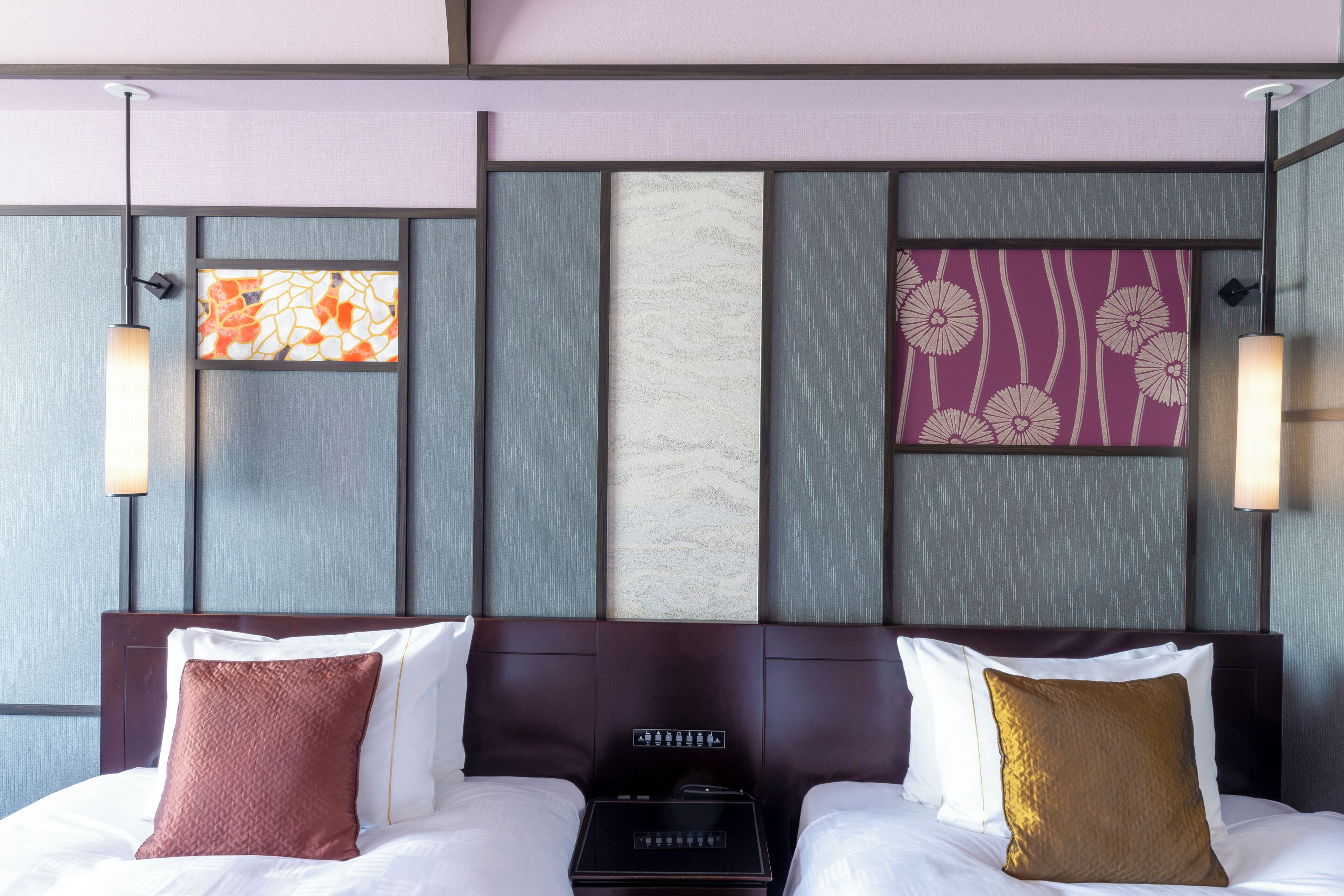 Habitación de hotel con cama, dos almohadas, panel de control y paneles decorativos en la pared.
