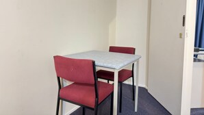 A small room with a single table and two chairs, a door, and a blue curtain. - Edinburgh Motor Inn (Warragul)