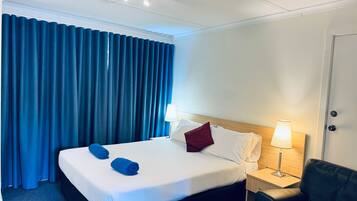 Una habitación de hotel con una cama, un escritorio, una silla, una lámpara y una puerta.