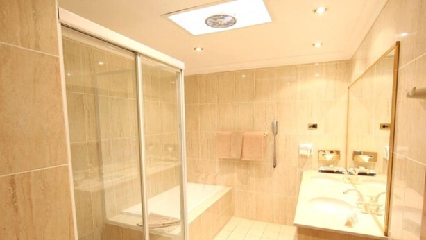 A modern bathroom with a glass shower enclosure, a bathtub, and a vanity with a large mirror. - The Hermitage Motel (Leumeah)