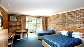 A hotel room with two beds, a desk, a chair, and a small table.