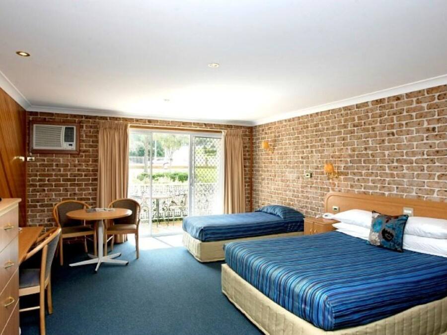 A hotel room with two beds, a desk, a chair, and a small table.