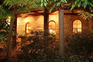 Un edificio de piedra con ventanas arqueadas y un jardín con árboles y plantas.