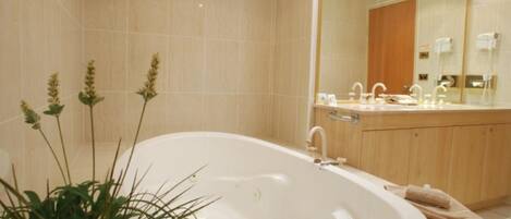 Un baño moderno con una bañera independiente, un espejo grande y un tocador de madera con lavamanos.