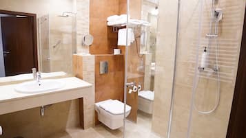 A modern bathroom with a glass-enclosed shower, a sink, and a toilet.