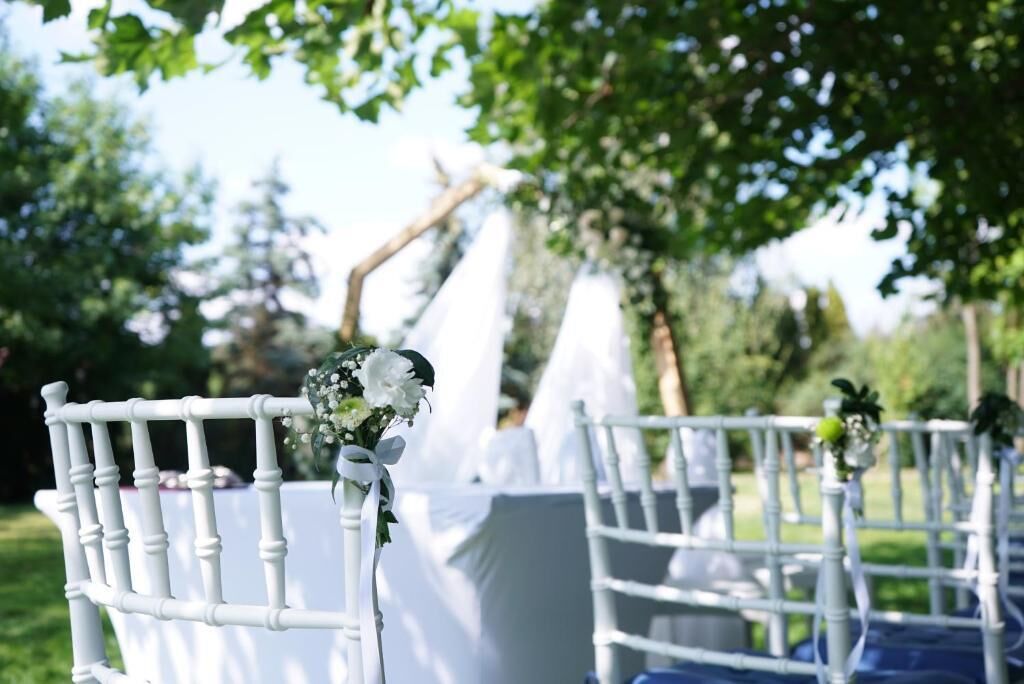 A white chair with a floral decoration and a white table in an outdoor setting.
