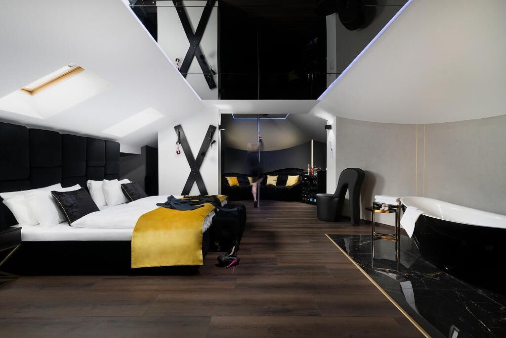 A modern hotel room with a bed, a desk, and a seating area.