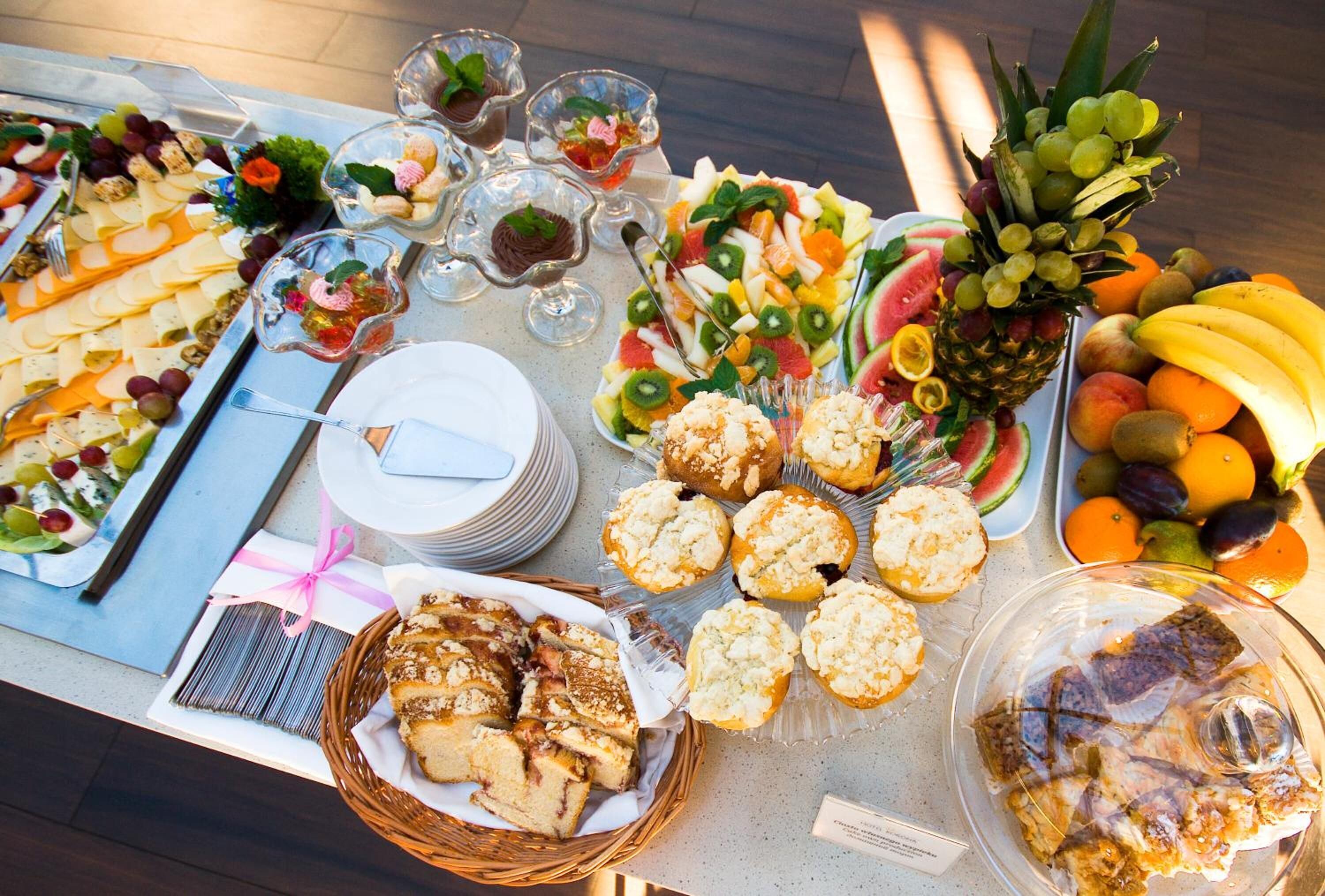 A buffet table with various food items including fruits, pastries, and desserts.