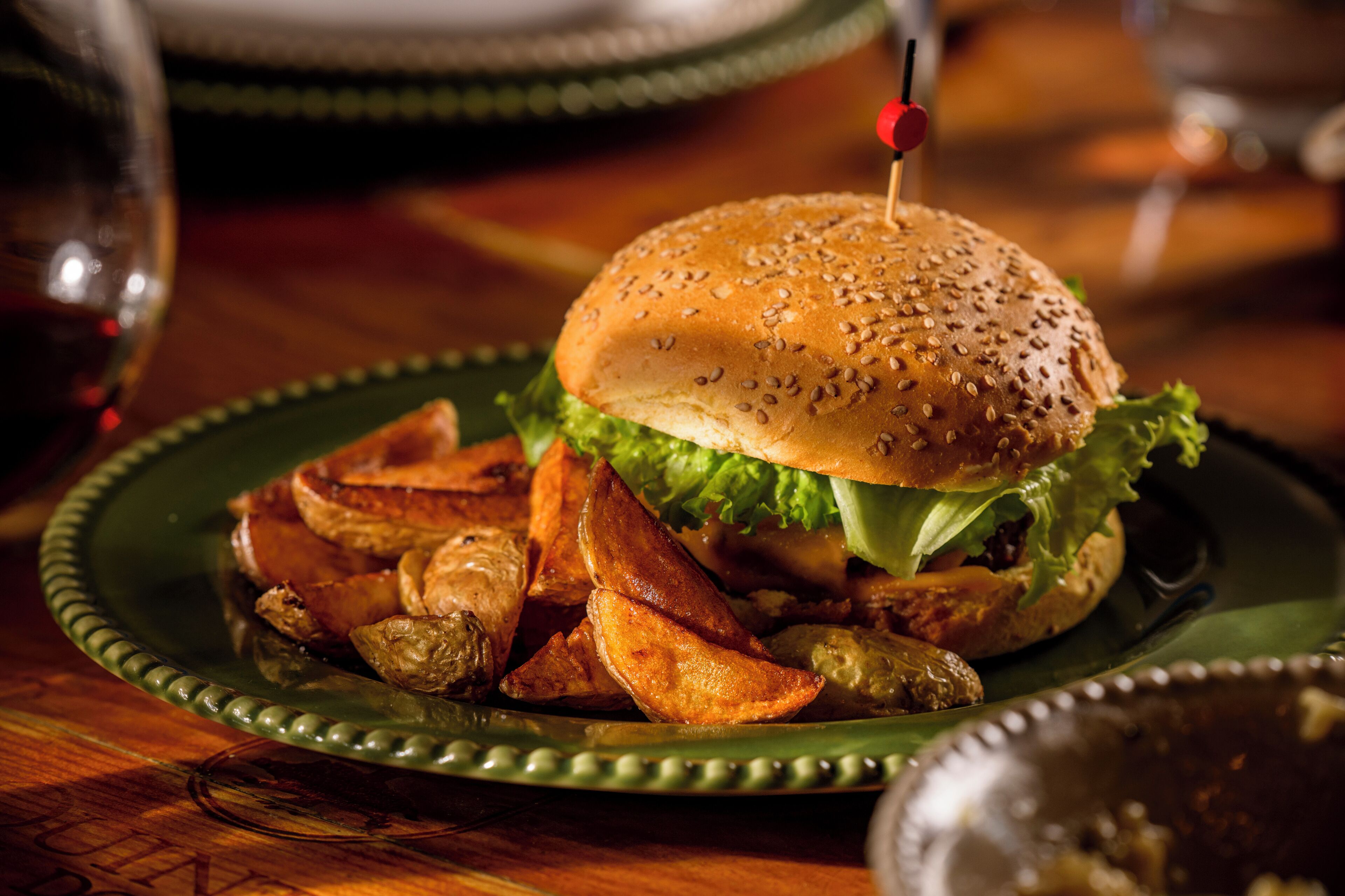 A plate with a burger, fries, and pickles.