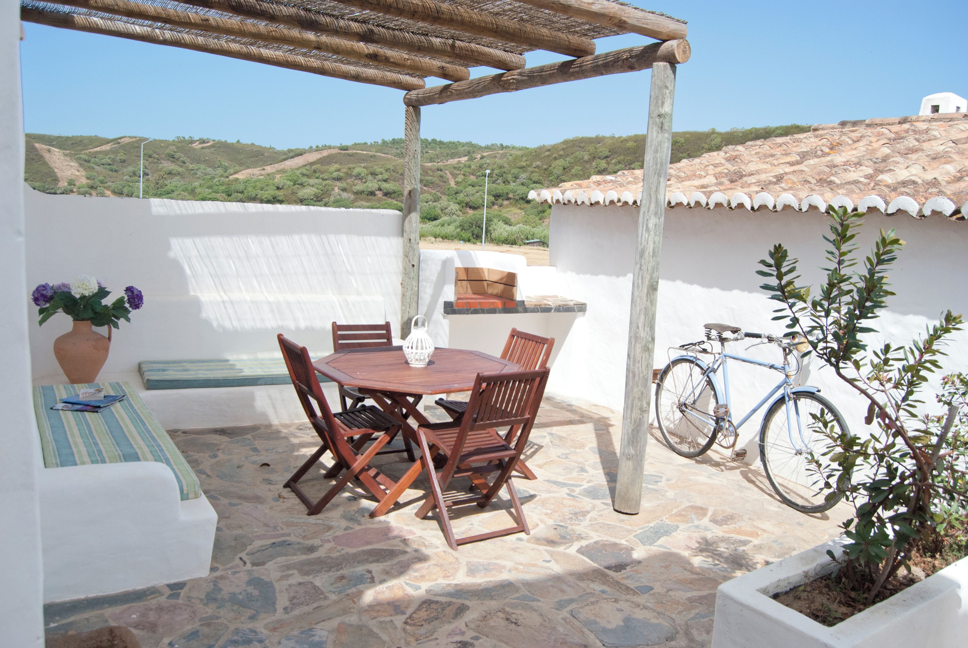 A patio with a table and chairs, a bicycle, and a potted plant.