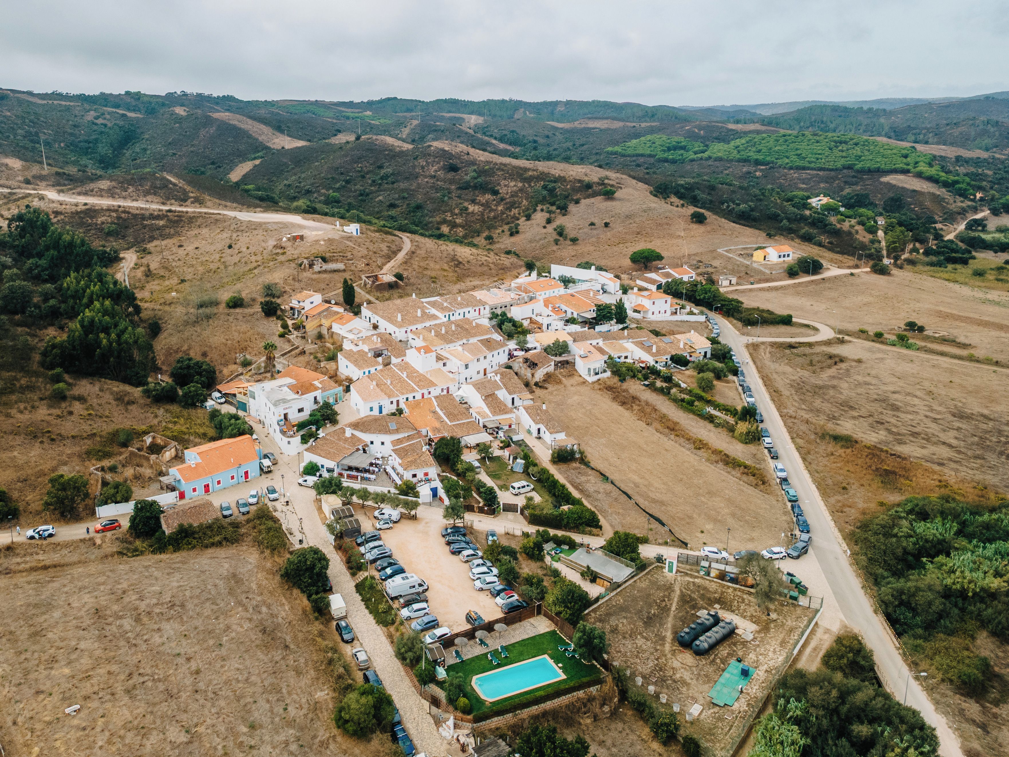 An aerial view of a residential area with houses, a swimming pool, and a parking lot.