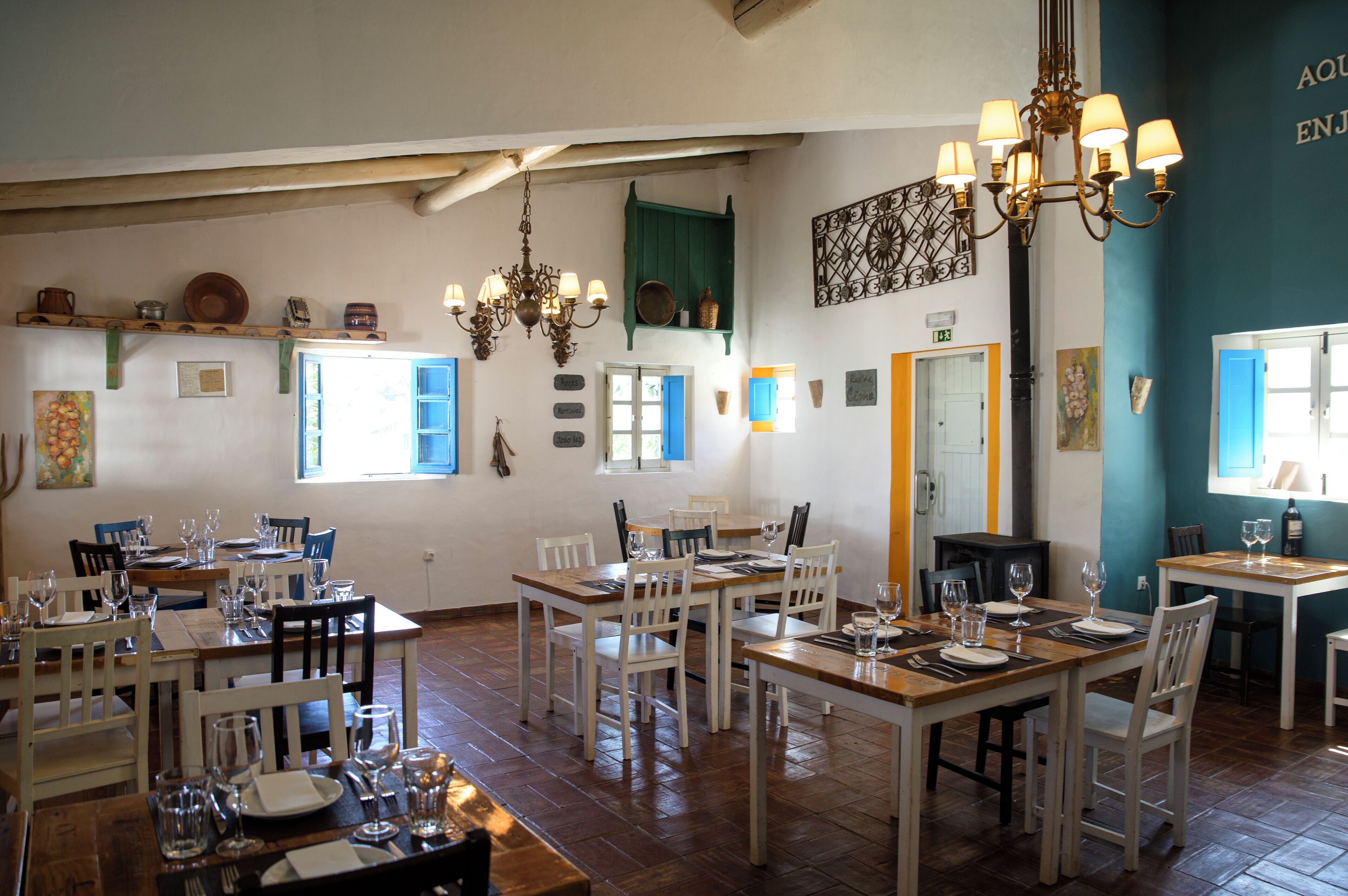 Un comedor con varias mesas y sillas, una araña y diferentes adornos en las paredes.