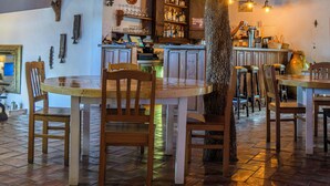 Un restaurant avec des tables et des chaises en bois, un coin bar et un plafond rouge.
