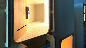 A compact, modern room with a wooden floor, a bed, and a small seating area. - Heart of Gold Hostel Berlin (Berlin)