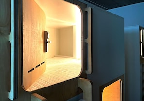 A compact, modern room with a wooden floor, a bed, and a small seating area. - Heart of Gold Hostel Berlin (Berlin)