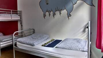 A dormitory room with bunk beds, a wall mural, and a red curtain.