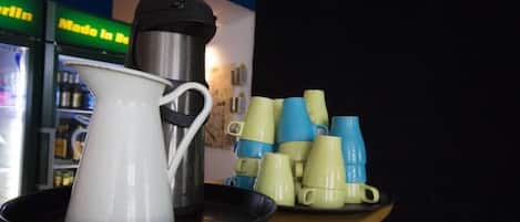 Una estación de café con una cafetera, una jarra blanca y una bandeja de tazas.