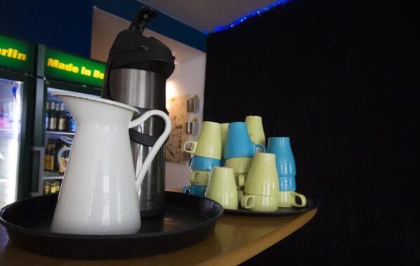 Una estación de café con una cafetera, una jarra blanca y una bandeja de tazas.