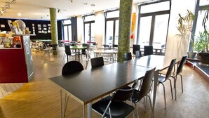 A spacious dining area with multiple tables and chairs, a counter with various items, and large windows allowing natural light. - Heart of Gold Hostel Berlin (Berlin)