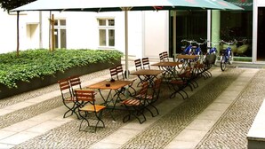 An outdoor seating area with tables and chairs, a covered umbrella, and a bicycle rack. - Heart of Gold Hostel Berlin (Berlin)