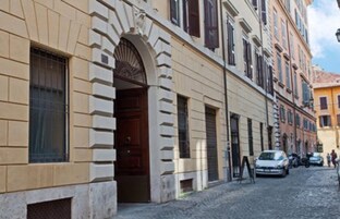 A historic building with a stone facade, a prominent arched entrance, and a cobblestone street.
