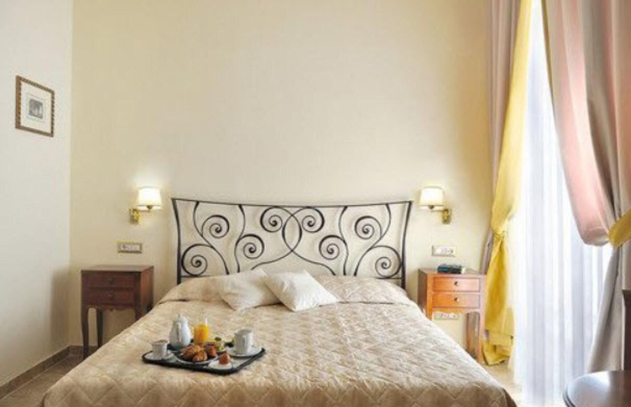 Quarto de hotel com cama, mesas de cabeceira, um serviço de jantar com itens de café da manhã e cortinas.