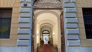 A building entrance with an arched doorway, a red carpet, and potted plants. - Hotel Le Clarisse al Pantheon (Rome)