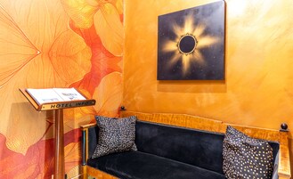 Et hotelreceptionsområde med en sofa, et skilt der står "HOTEL INFO", og en væg med et sol-lignende design.