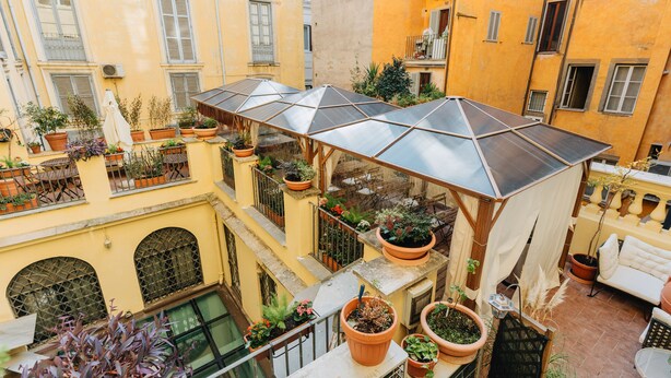 A multi-level courtyard with potted plants, a covered seating area, and a pool. - Hotel Le Clarisse al Pantheon (Rome)