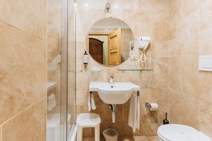 A modern bathroom with a glass shower enclosure, a white sink, a toilet, and a mirror.
