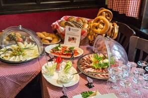 Una mesa de buffet con diversos alimentos, como quesos, ensaladas, carnes y pan.