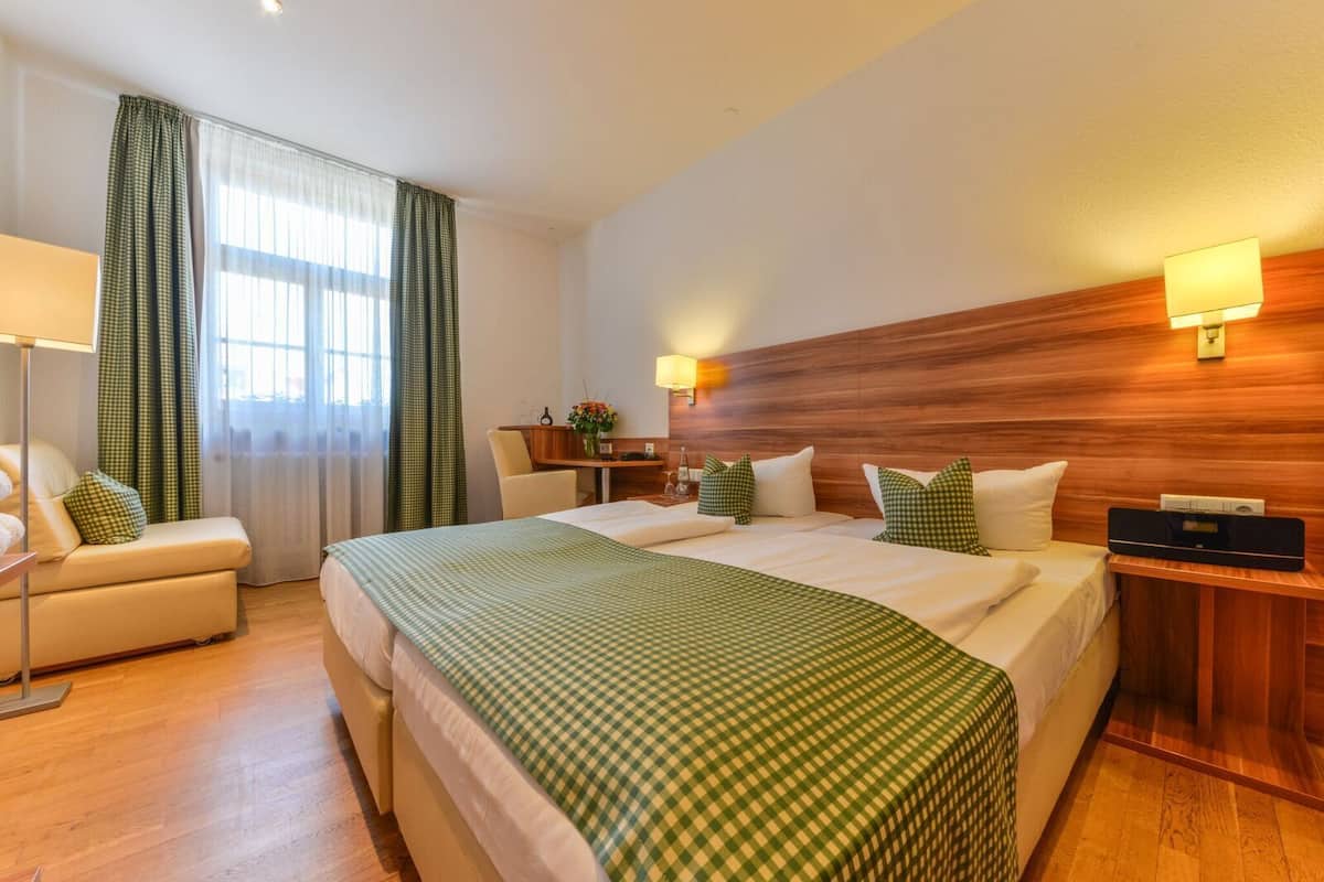 Una habitación de hotel con una cama grande, un escritorio, una silla y una lámpara.