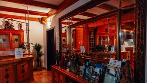 Un área de recepción con mostrador de madera, un espejo grande y exhibición de revistas y folletos.