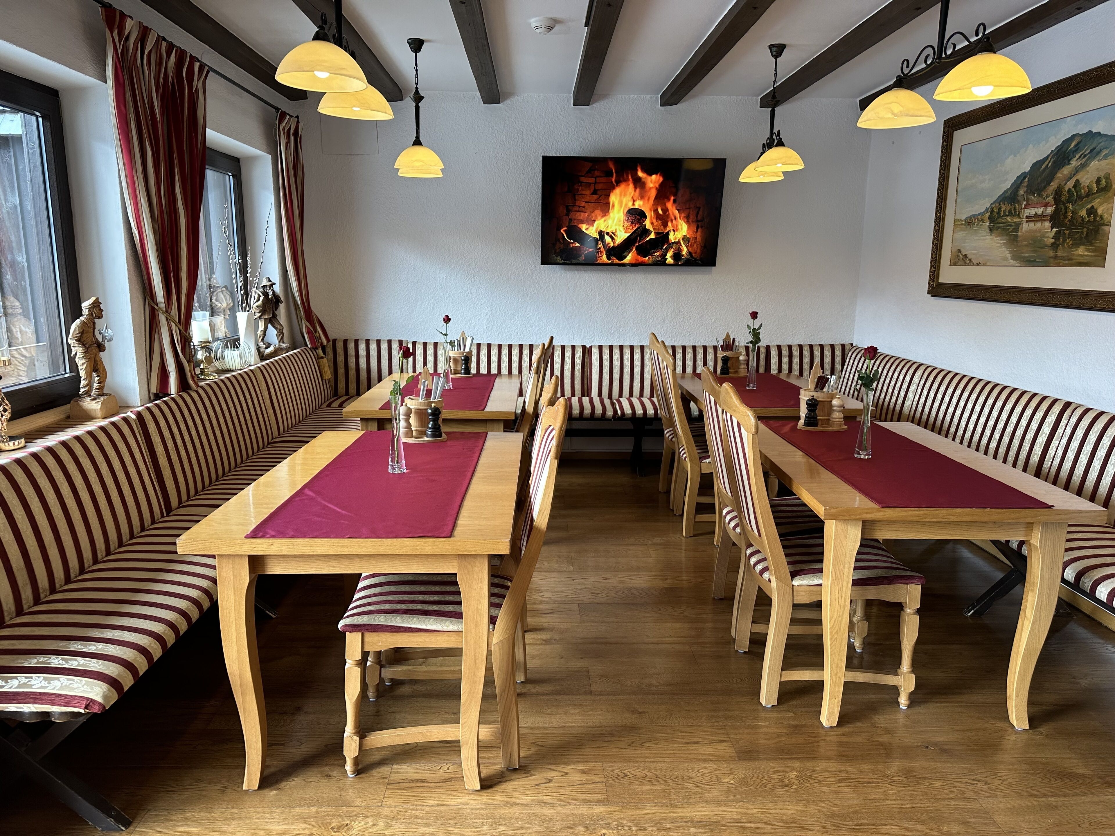 Un ristorante con sedute a righe, tavoli in legno, un camino e lampade a sospensione.