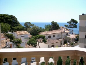 A coastal residential area with terracotta-tiled buildings, a clear view of the sea, and lush greenery. - Welikehotel Triton Beach (Capdepera)